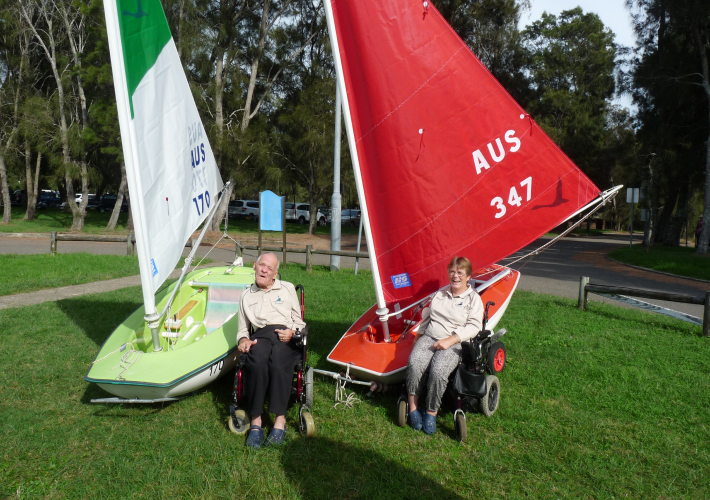 Two sailors posing with two sailboats